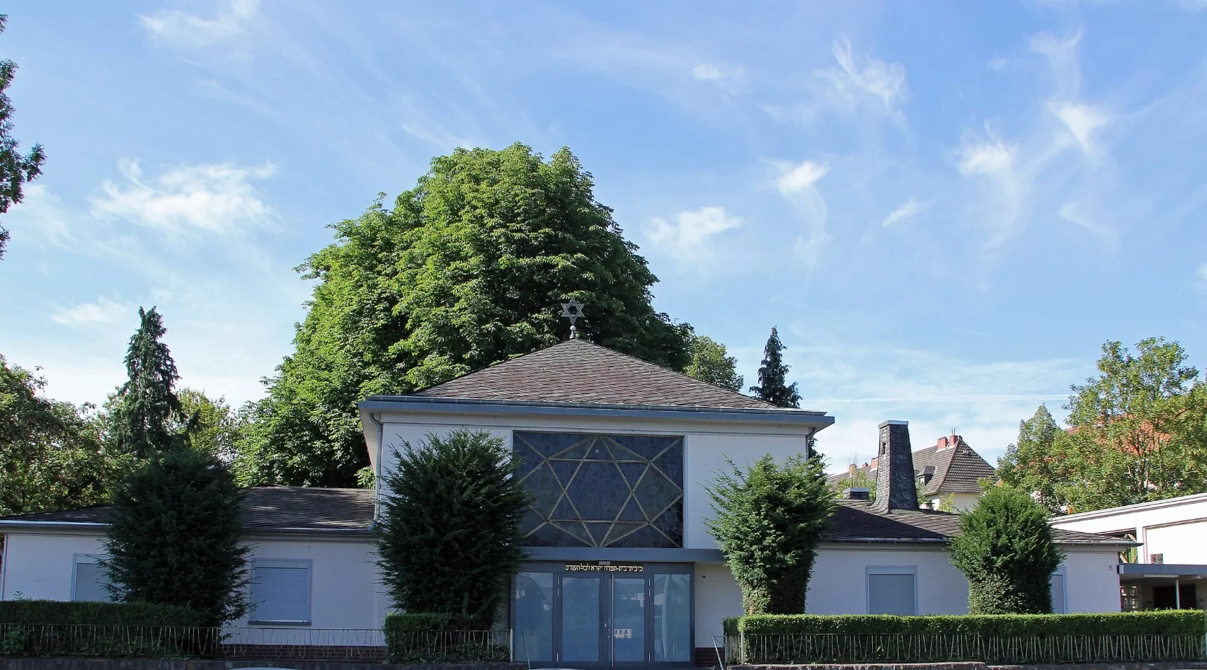 Eine Wissenschaftlerin und ein Wissenschaftler arbeiten hinter einer Glasfassade und mischen Chemikalien mit Großgeräten.