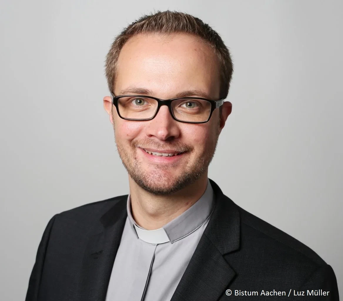 Eine Wissenschaftlerin und ein Wissenschaftler arbeiten hinter einer Glasfassade und mischen Chemikalien mit Großgeräten.