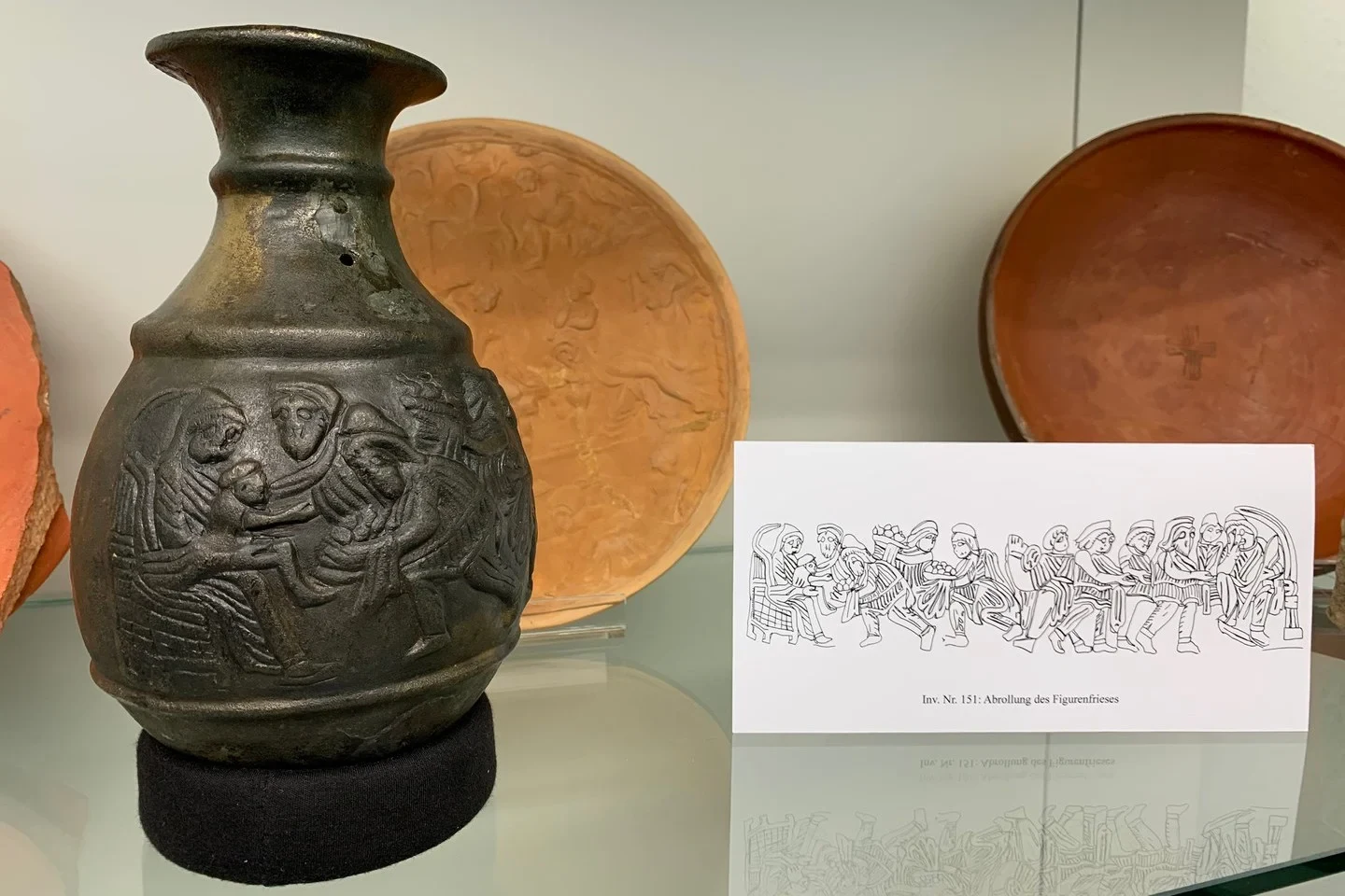 Eine Wissenschaftlerin und ein Wissenschaftler arbeiten hinter einer Glasfassade und mischen Chemikalien mit Großgeräten.